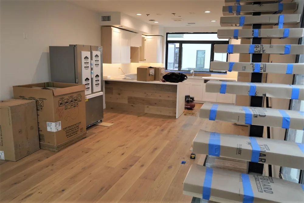 Wide-plank European white oak engineered hardwood running through an open kitchen and living area in Los Angeles, with stair treads protected during construction