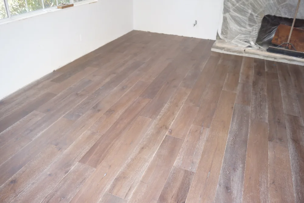 Finished dark wide-plank hardwood flooring along the window wall of a Pasadena living room