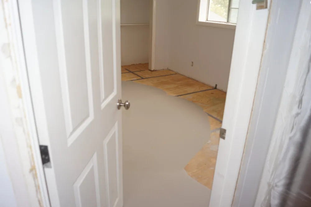 Floor-leveling compound over a taped plywood subfloor seen through a doorway in a Pasadena home