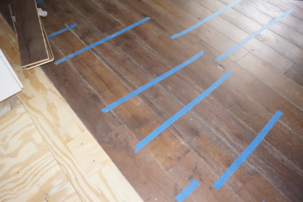 Dark hardwood flooring during installation in Pasadena, California, with temporary blue tape helping maintain plank alignment