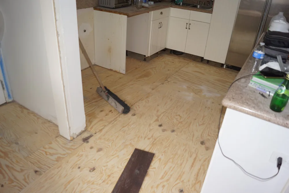 Plywood subfloor in a Pasadena kitchen being cleaned before hardwood flooring installation