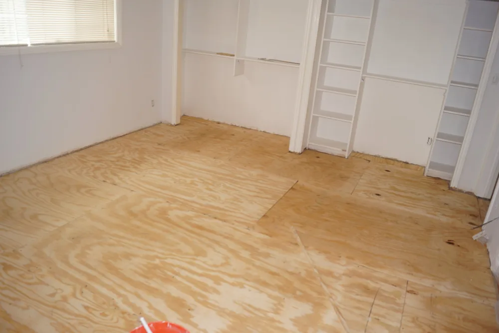 Exposed plywood subfloor in a Pasadena bedroom during preparation for hardwood flooring installation