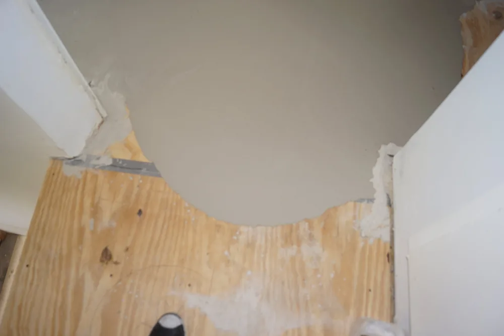 Close view of cured floor-leveling compound meeting a plywood subfloor during a Pasadena hardwood flooring project