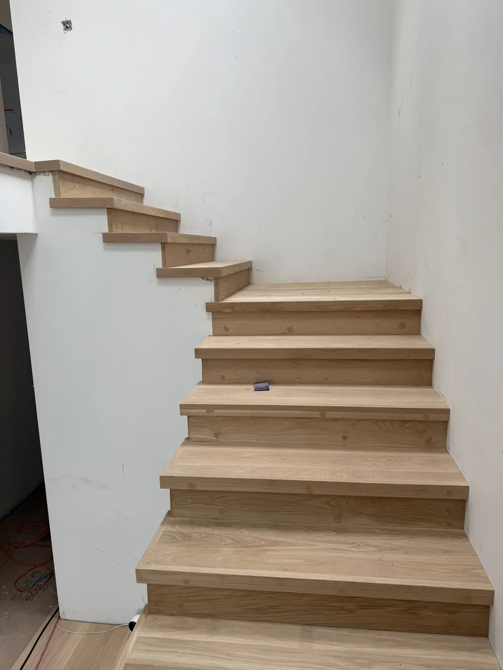 White oak stair treads and wood risers where the staircase turns toward the upper flight, during installation