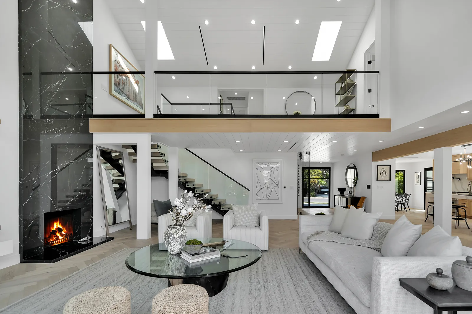 Two-story living room with herringbone European oak hardwood floors, porcelain slab fireplace and open loft