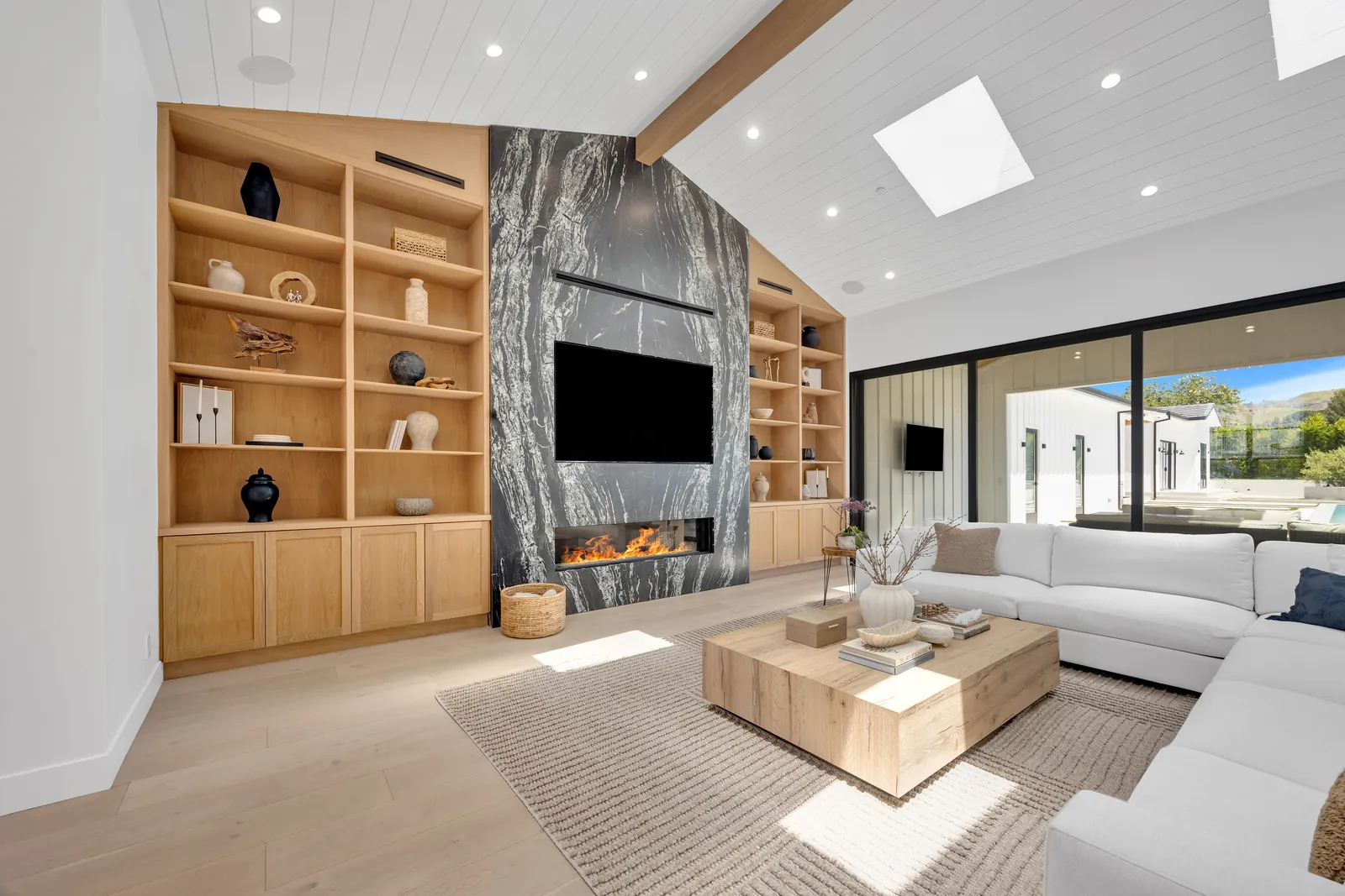 Fireplace wall with white oak built-ins over wide-plank light oak hardwood flooring