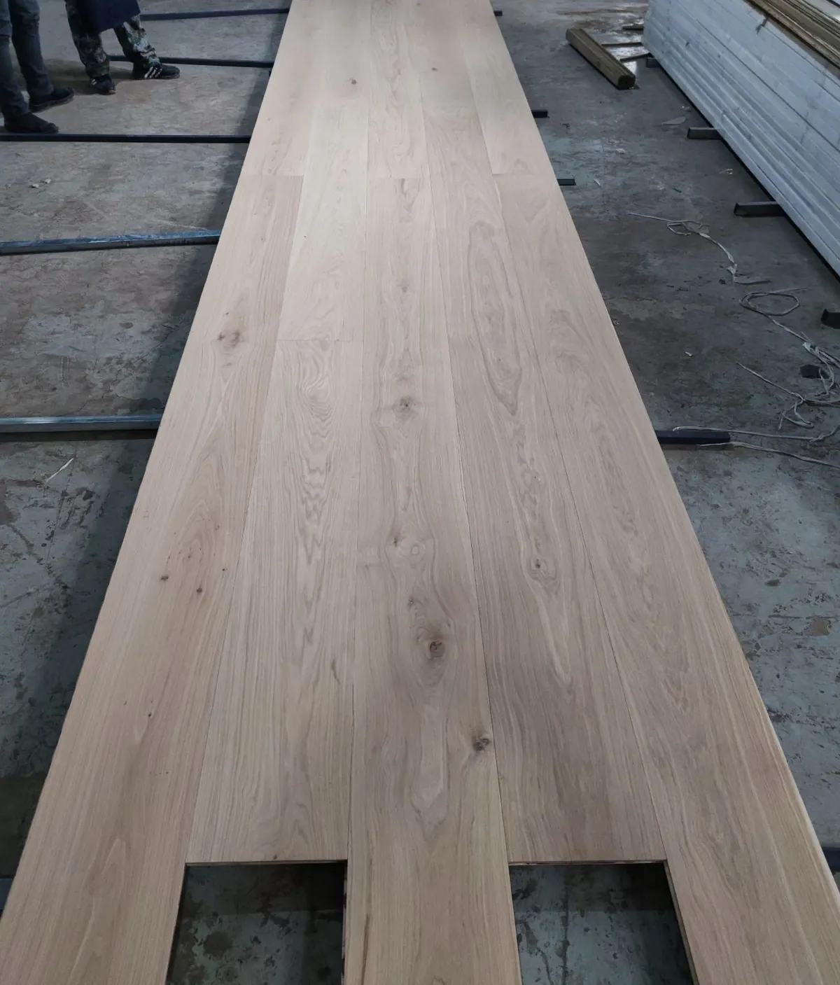 Wide-plank oak flooring boards laid out on a floor to check knots and grade