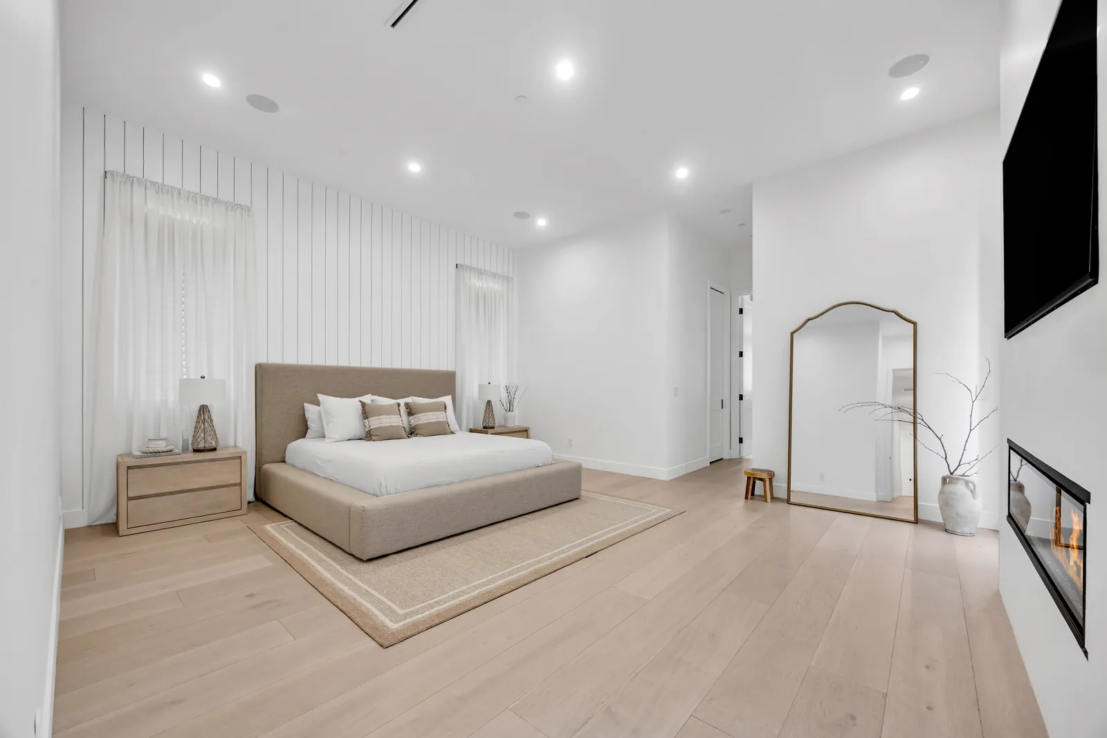 Primary bedroom with board-and-batten wall and wide-plank oak floors